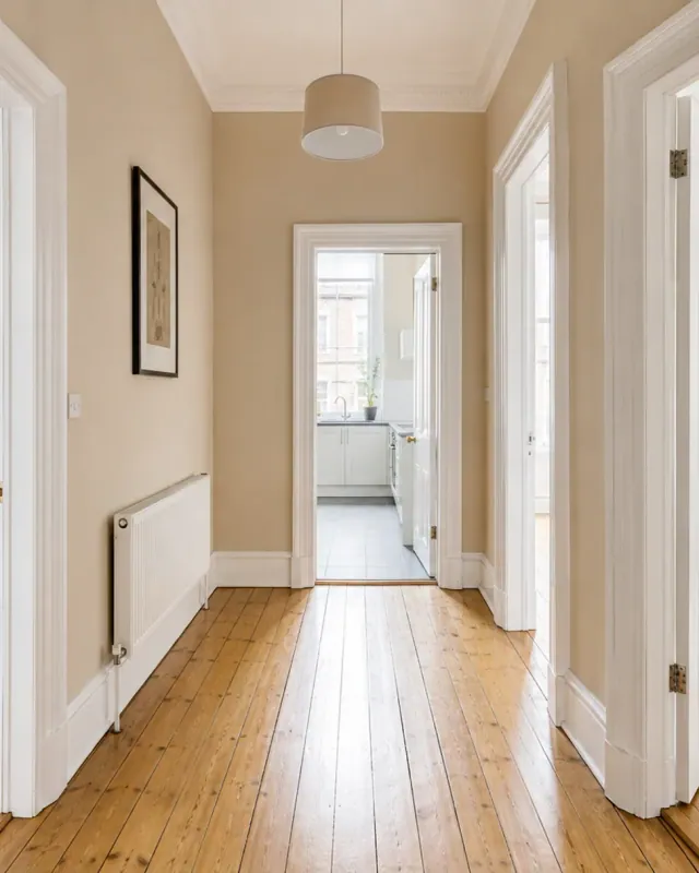 A cleaned tenement hallway with polished floorboards, doors standing open to a bedroom and a kitchen